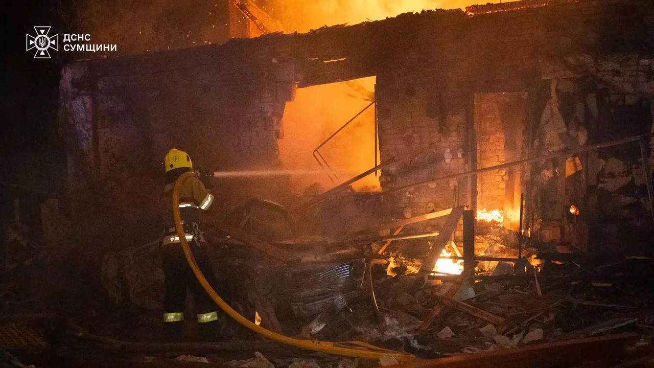 Ein Feuerwehrmann richtet seinem Löschschlauch in eine brennende Hausruine