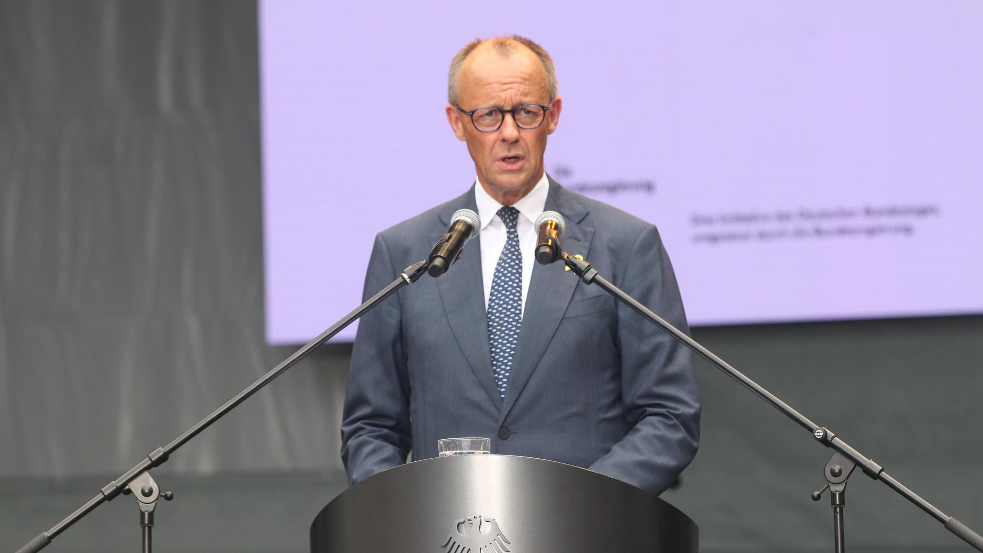 Bundeskanzler Friedrich Merz spricht während einer Rede in zwei Mikrofone.