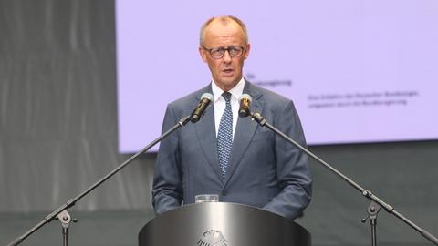 Bundeskanzler Friedrich Merz spricht während einer Rede in zwei Mikrofone.