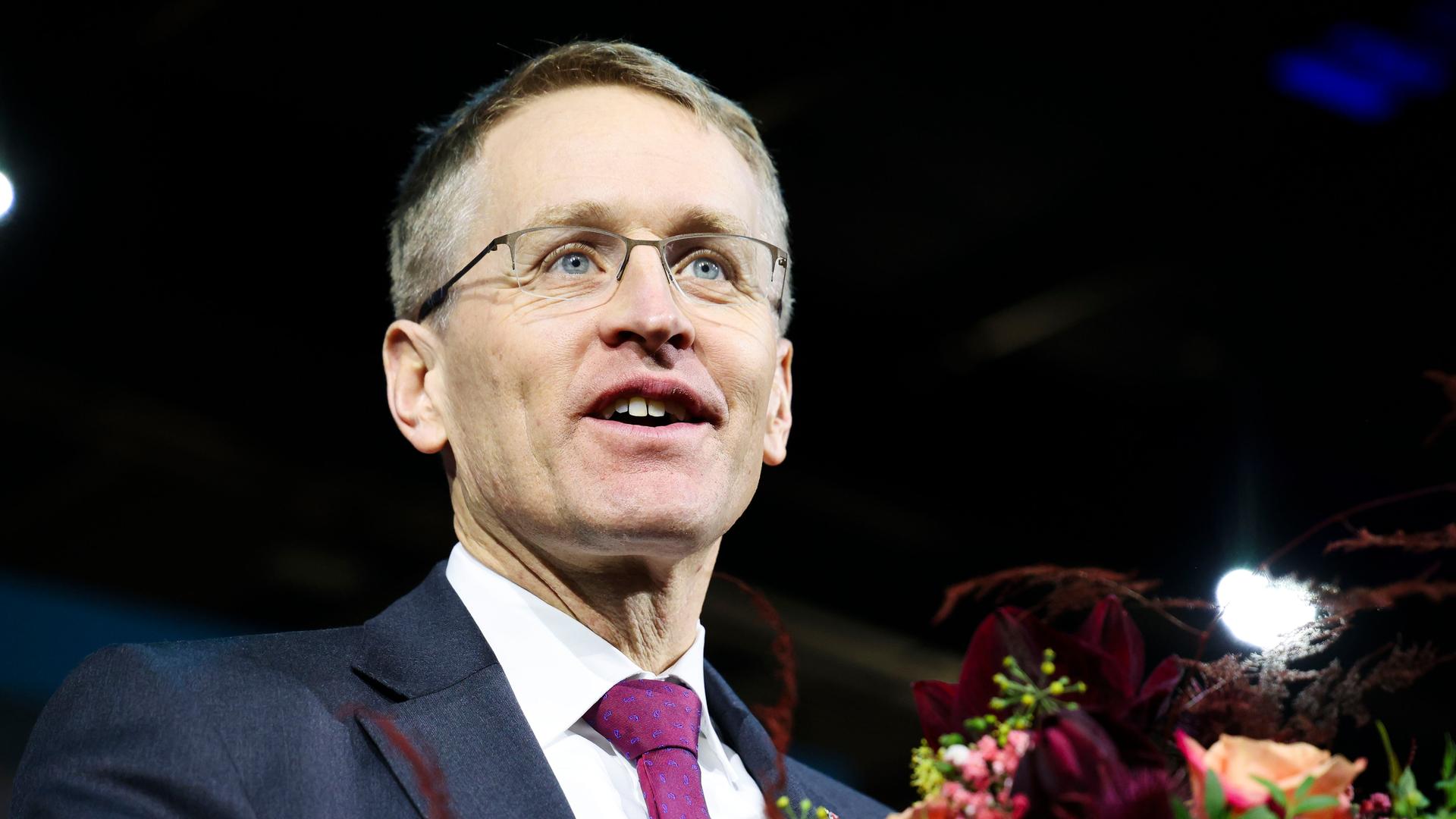 Daniel Günther (CDU), Ministerpräsident von Schleswig-Holstein, steht mit einem Blumenstrauß auf der Bühne und lächelt.