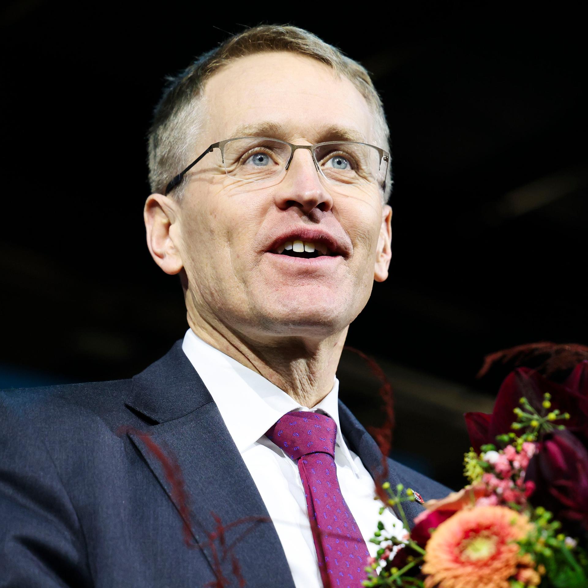 Daniel Günther (CDU), Ministerpräsident von Schleswig-Holstein, steht mit einem Blumenstrauß auf der Bühne und lächelt.