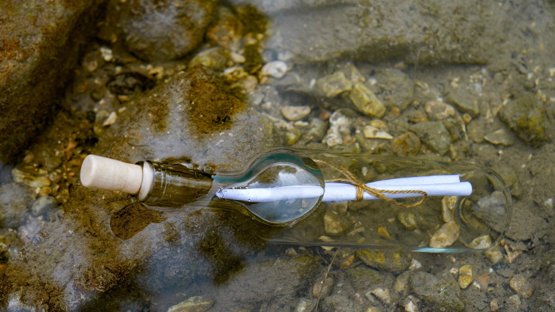 Flaschenpost im Wasser schwimmend auf den Felsen am Meeresstrand Flaschenpost im Wasser schwimmend auf den Felsen am Meeresstrand