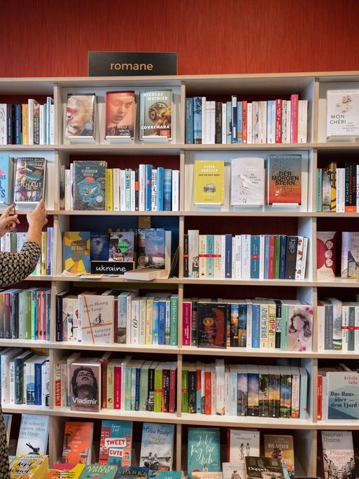 Eine Frau nimmt in einer Buchhandlung in Frankfurt am Main einen Roman aus dem Verkaufsregal.