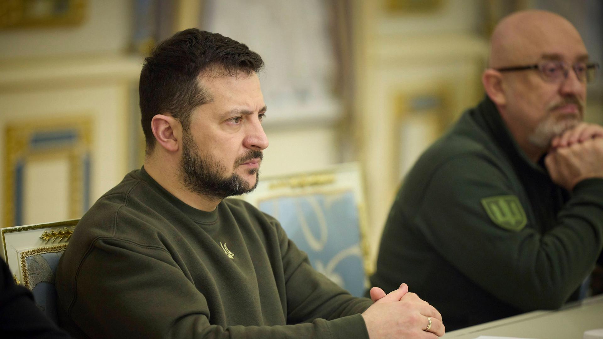 Präsident Selenskyj sitzt an einem Tisch, rechts daneben sitzt Oleksij Resnikow, bisher Verteidigungs-Minister.