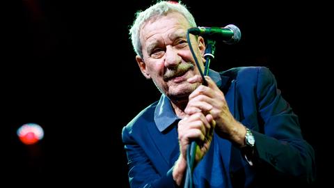 Der italienische Sänger Paolo Conte beim 52. Montreux Jazz Festival. Er hält das Mikro mit beiden Händen umschlungen und lächelt ins Publikum. 