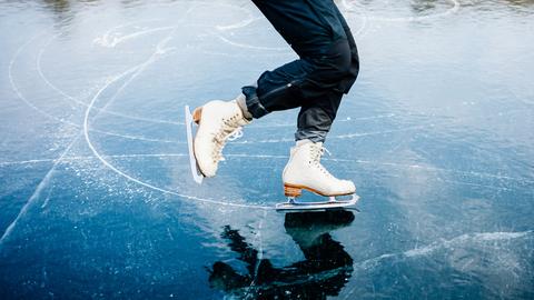 Schlittschuhkufen schneiden Kurven und Spiralen in einen zugefrorenen See.