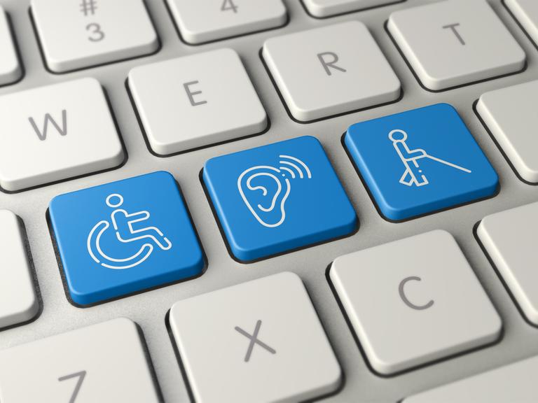 Computertastatur mit drei weißen Grafiken auf blauem Grund: ein Rollstuhl, eine Person mit Langstock, und einem Symbol für Schwerhörigkeit