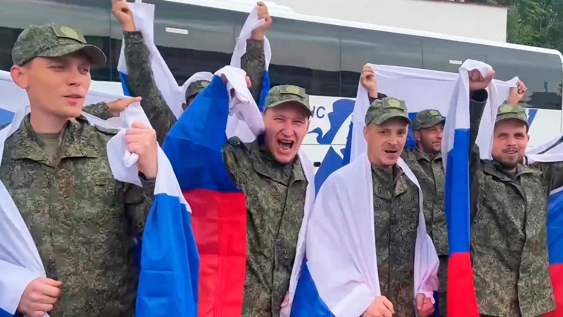 Einige russische Gefangene feiern mit Landesfahnen ihre Freilassung.