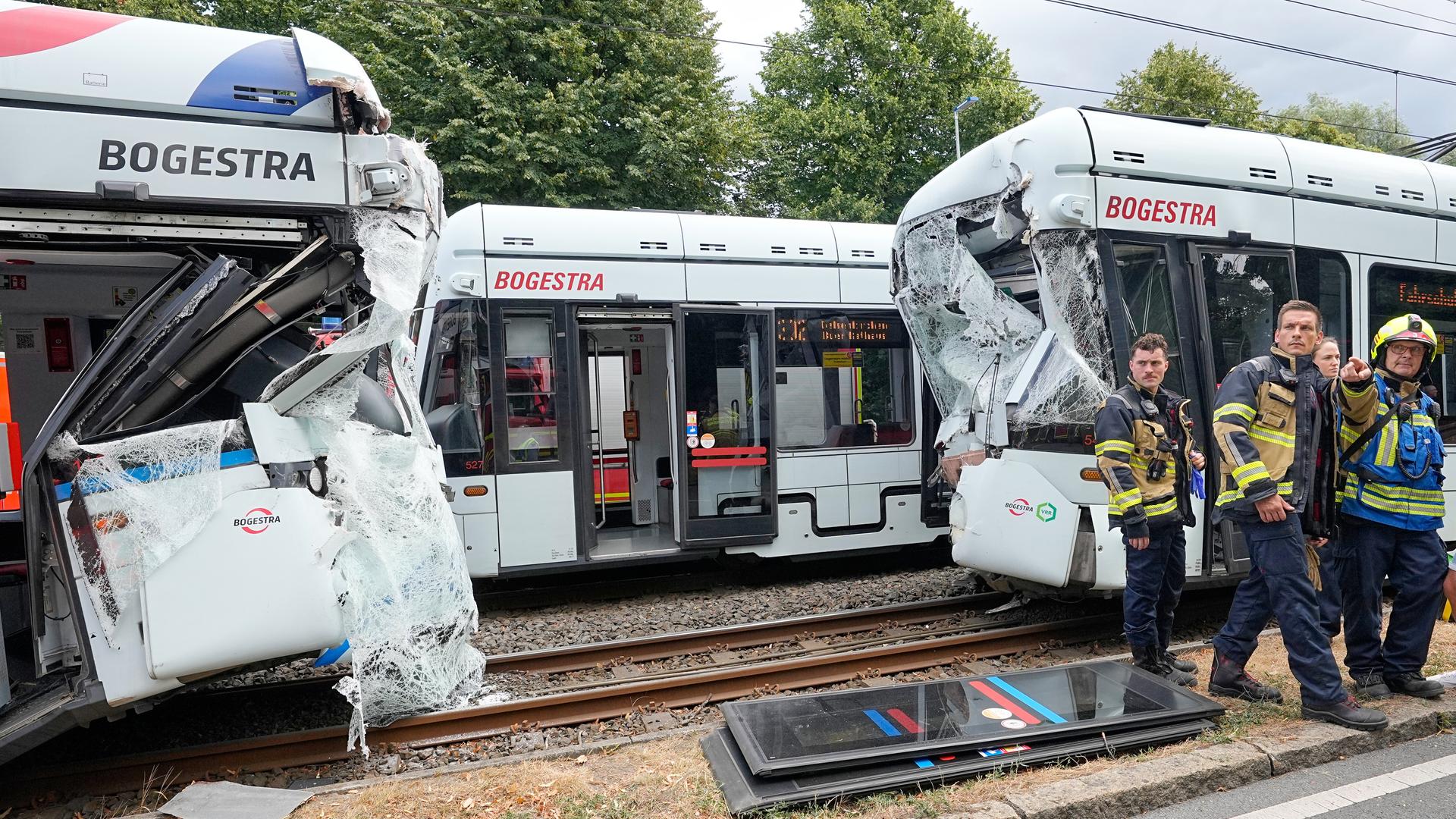 Rettungskräfte stehen vor zwei beschädigten Straßenbahn-Waggons. Rettungskräfte stehen vor zwei beschädigten Straßenbahn-Waggons.