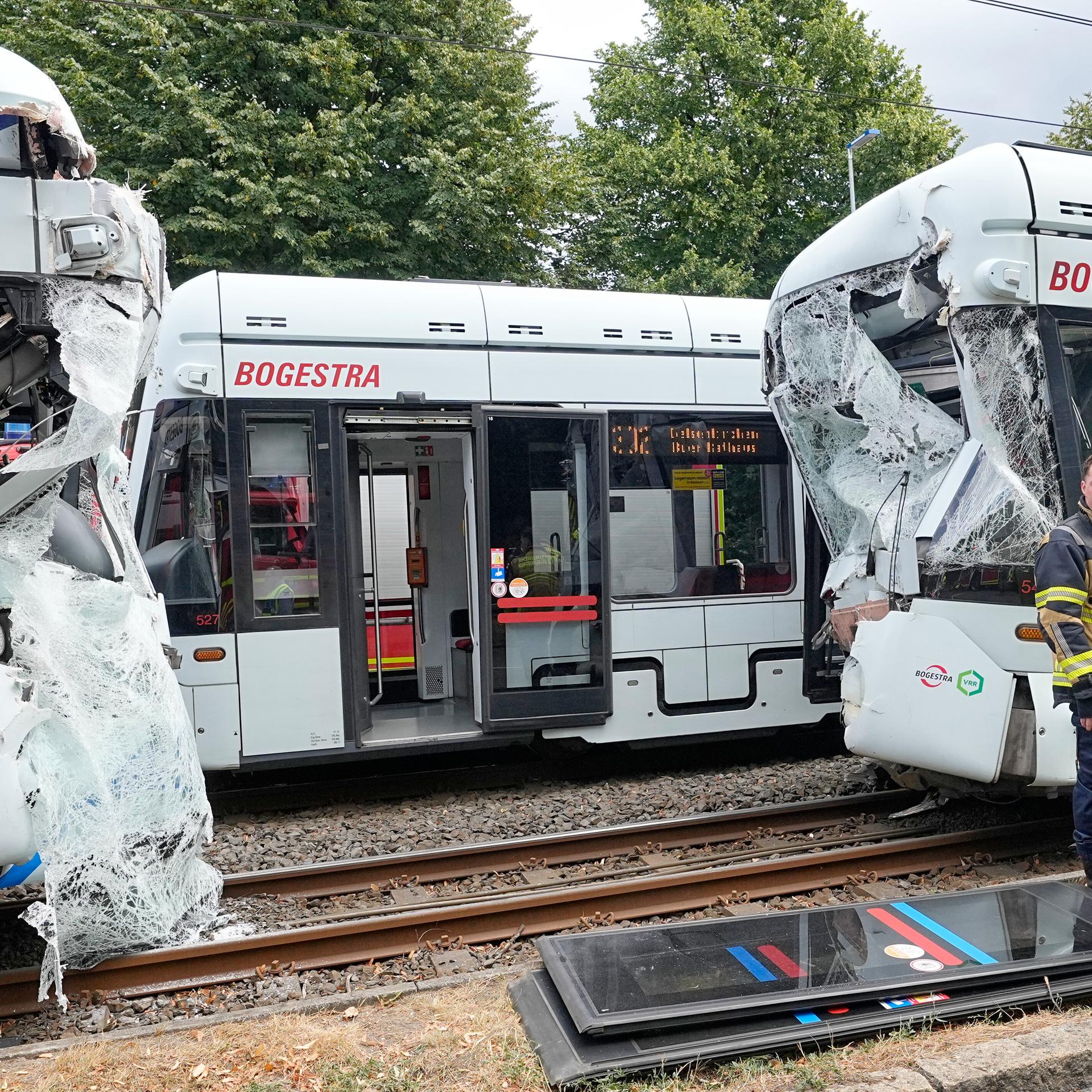Rettungskräfte stehen vor zwei beschädigten Straßenbahn-Waggons.