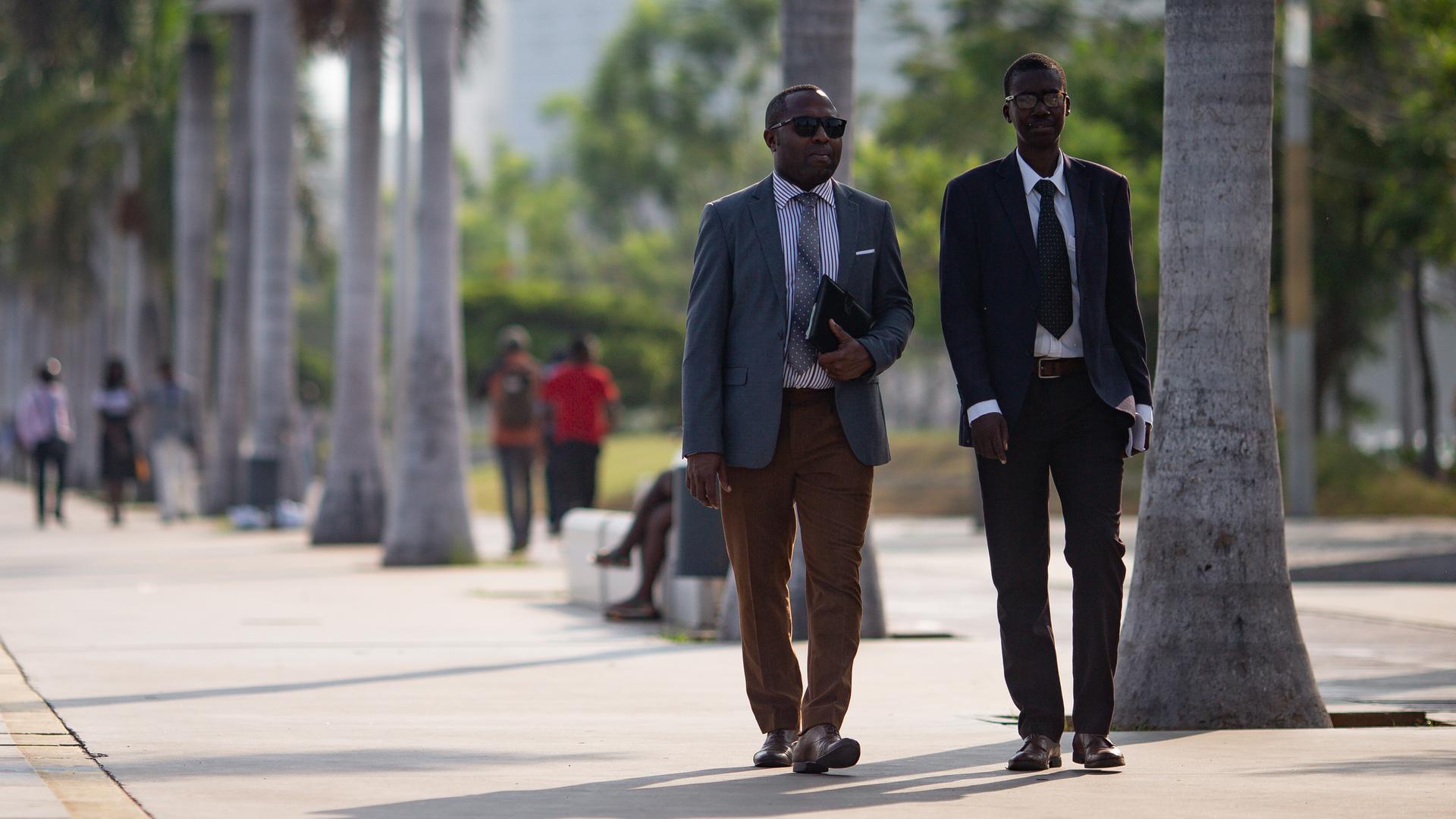 Zwei Geschäftsleute spazieren entlang der Bucht von Luanda in der Nähe der Avenida 4 de Fevereiro. 