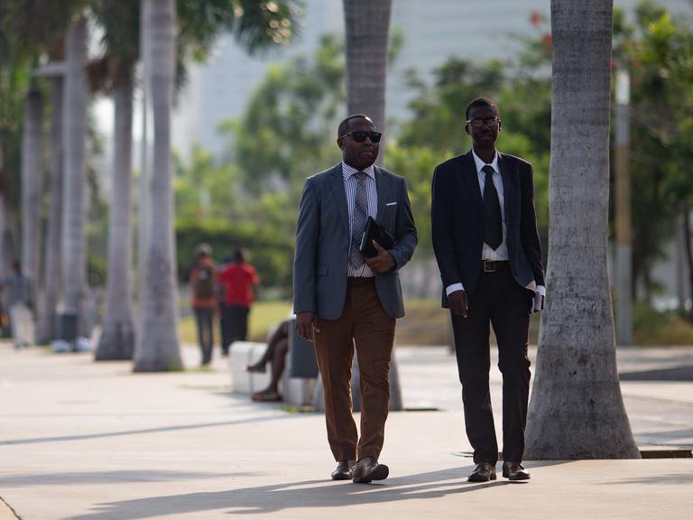 Zwei Geschäftsleute spazieren entlang der Bucht von Luanda in der Nähe der Avenida 4 de Fevereiro. 