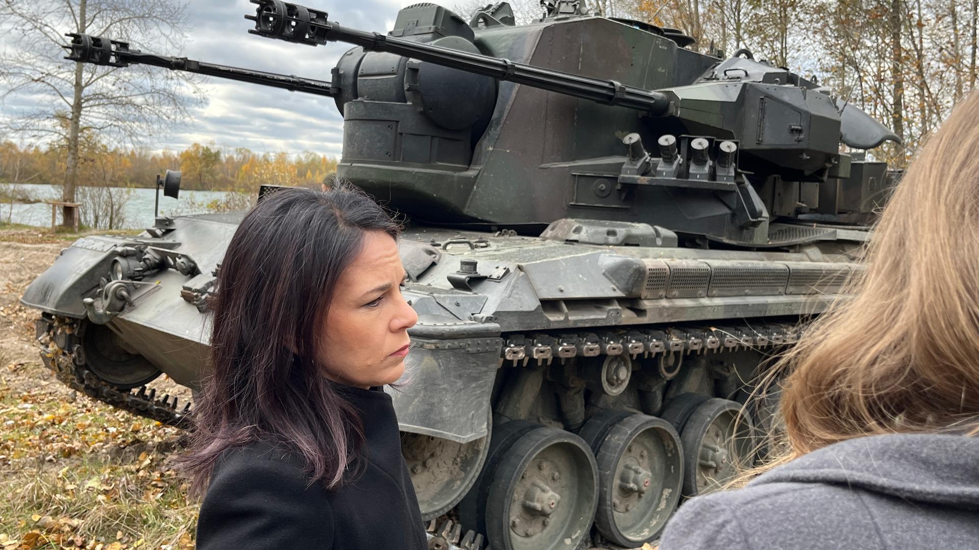 Bundesaußenministerin Baerbock steht neben einem Panzer.