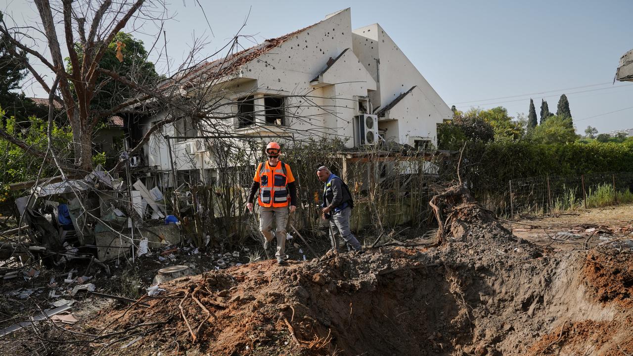 Feuerwehrleute inspizieren einen Krater nach einem Angriff.