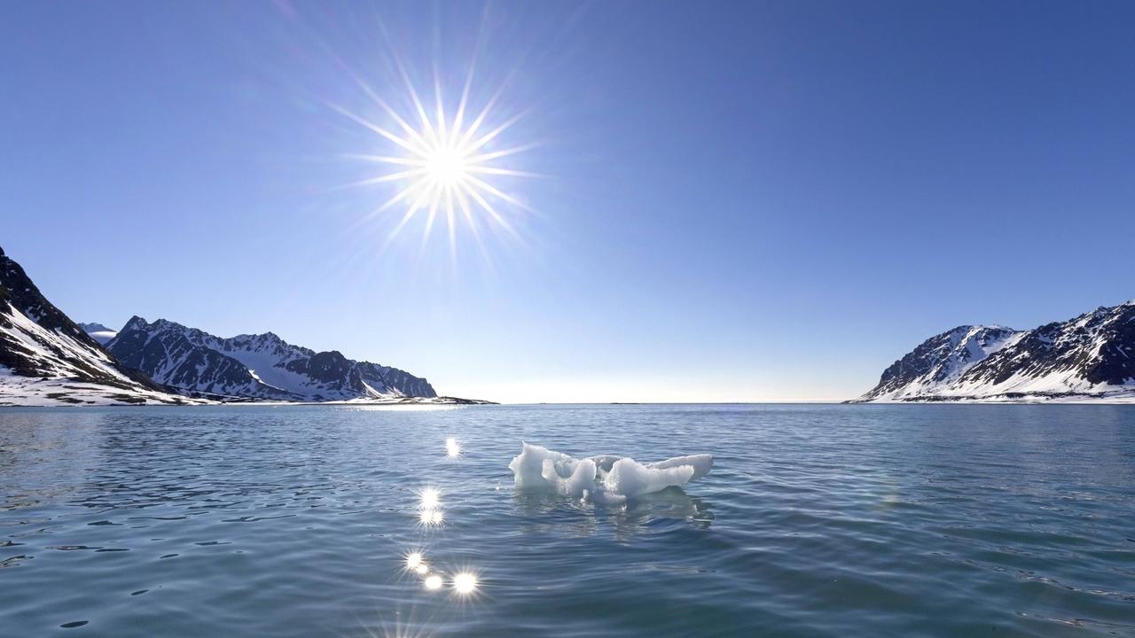 Schmelzendes Eis in der Arktis vor einem blauen Himmel, von dem die Sonne strahlt