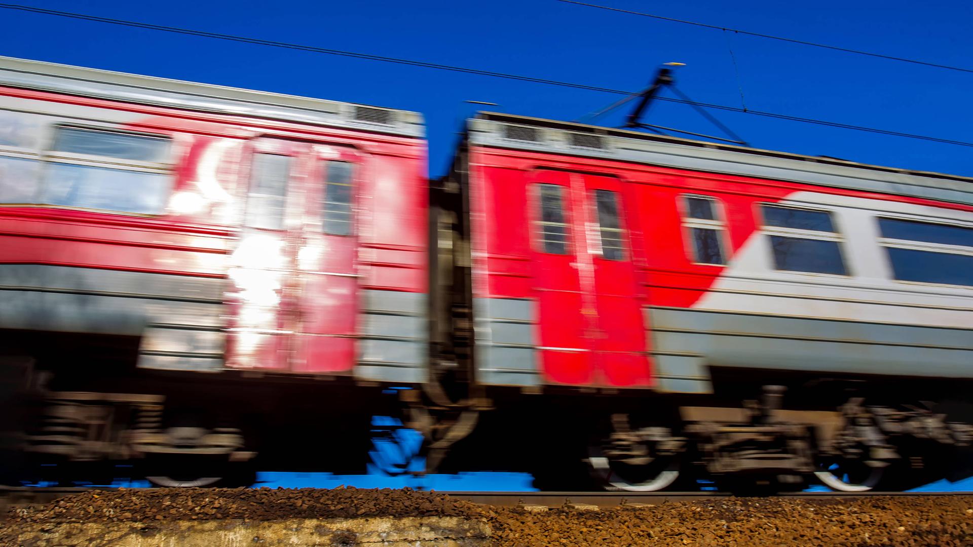 Zwei fahrende rote Waggons der Transsibirischen Eisenbahn auf einem Gleis. Sie fahren, dadurch hat das Bild eine Bewegungsunschärfe.