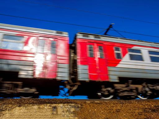 Zwei fahrende rote Waggons der Transsibirischen Eisenbahn auf einem Gleis. Sie fahren, dadurch hat das Bild eine Bewegungsunschärfe.