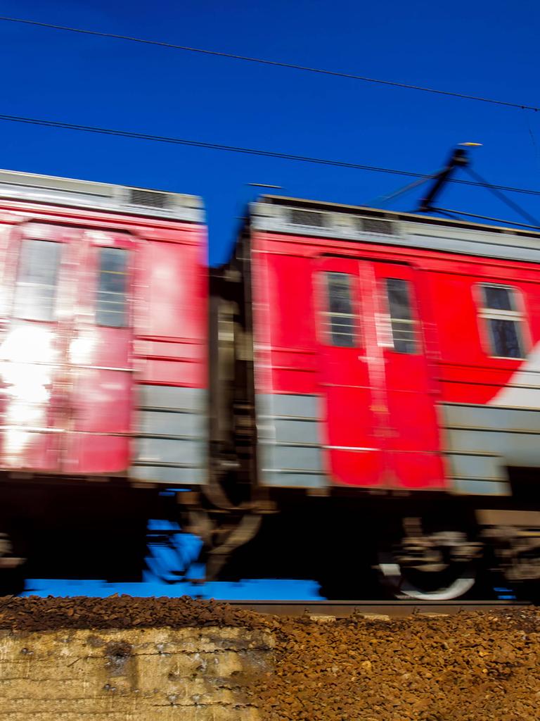 Zwei fahrende rote Waggons der Transsibirischen Eisenbahn auf einem Gleis. Sie fahren, dadurch hat das Bild eine Bewegungsunschärfe.