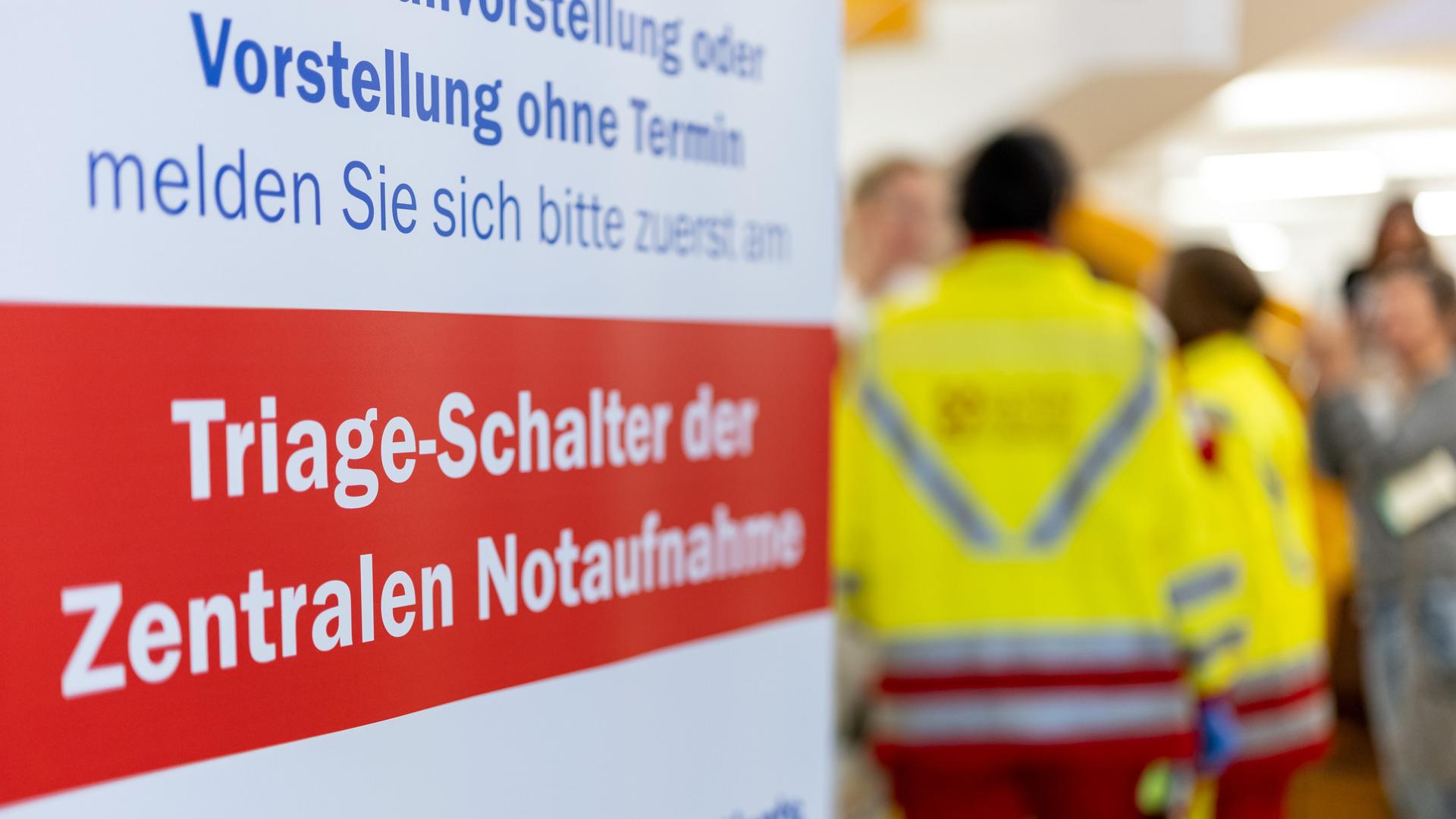 "Triage-Schalter der Zentralen Notaufnahme" steht auf einem Banner, im Hintergrund stehen Rettungskräfte. "Triage-Schalter der Zentralen Notaufnahme" steht auf einem Banner, im Hintergrund stehen Rettungskräfte.