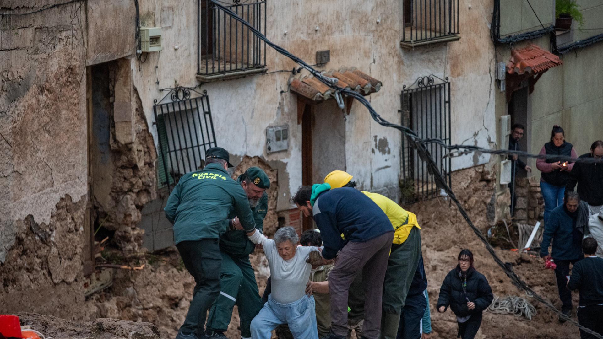 Rettungskräfte helfen einer Frau von einer durch Sturzfluten zerstörten Straße in Letur/Spanien wegzukommen. (29.10.2024)