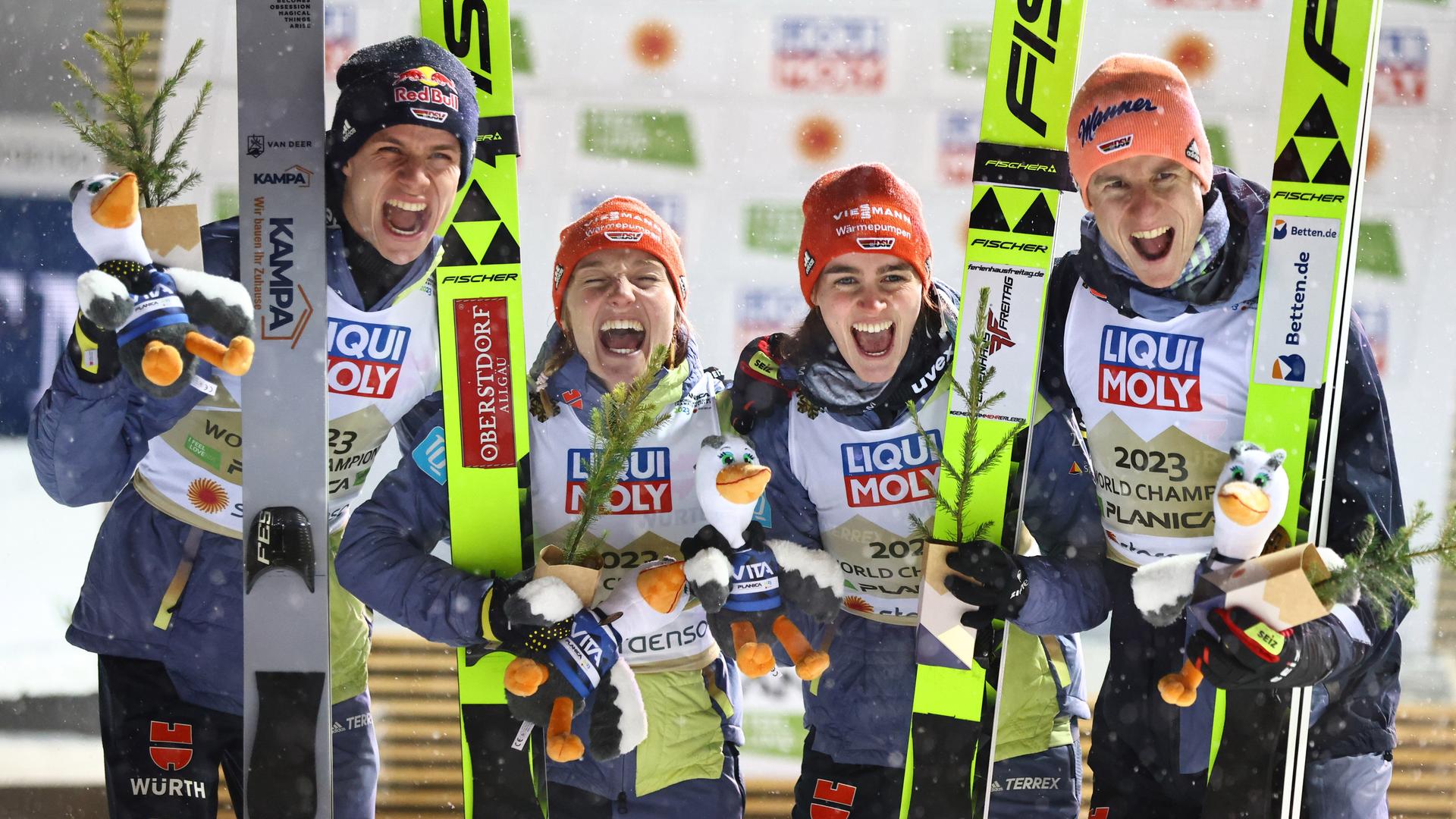 Die Ski-Springer Karl Geiger, Selina Freitag, Katharina Althaus, Andreas Wellinger aus Deutschland stehen zusammen und jubeln.