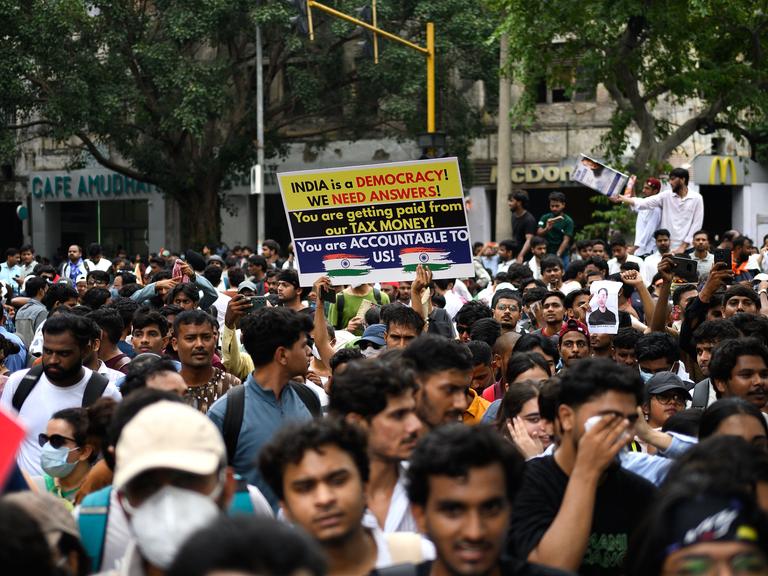 Aktivisten und Mitglieder der Kakerlaken-Partei halten in Neu Delhi Plakate hoch.