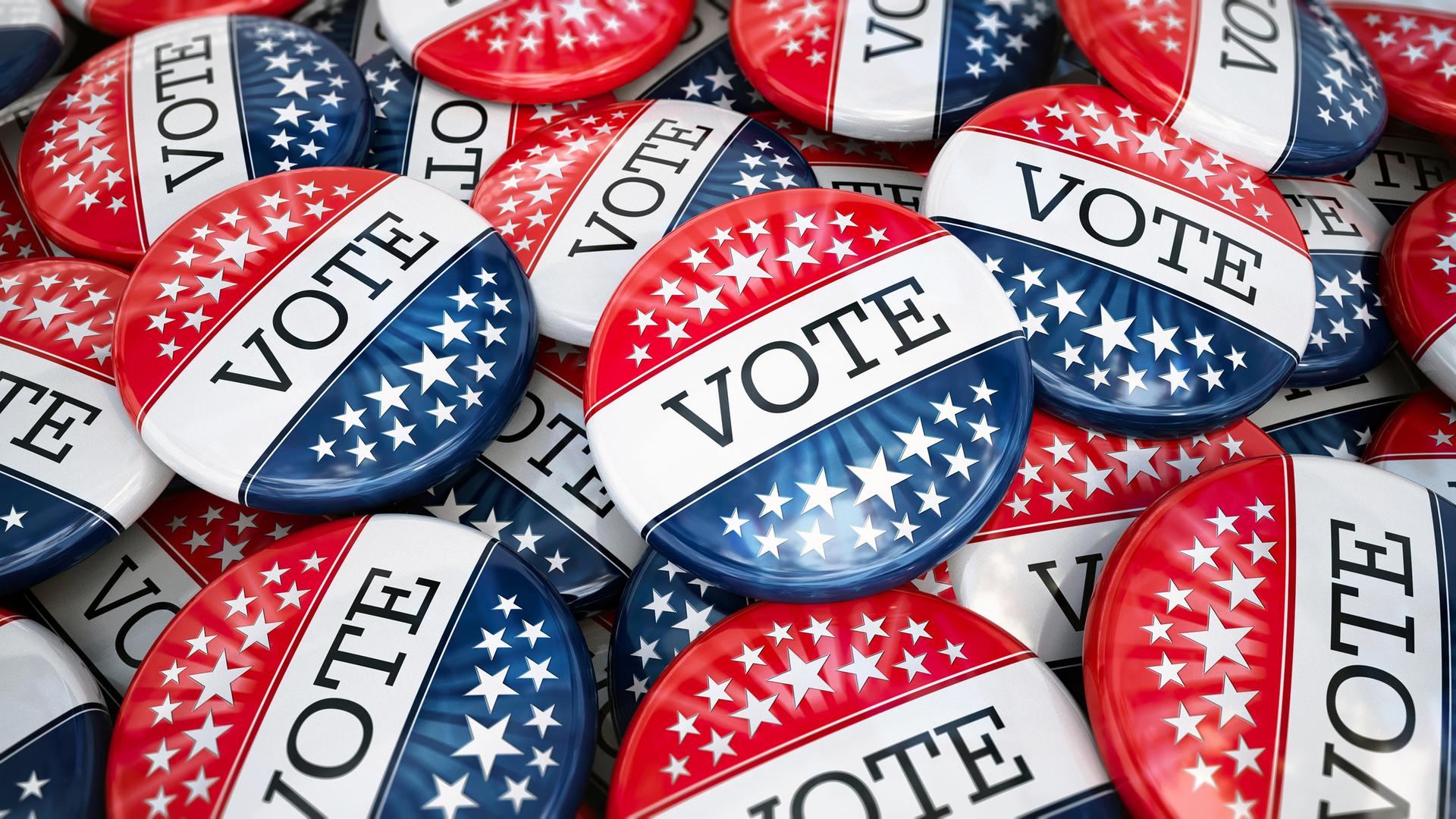 Großer Stapel von Wahlbuttons mit den Farben der amerikanischen Flagge. Darauf steht "Vote".