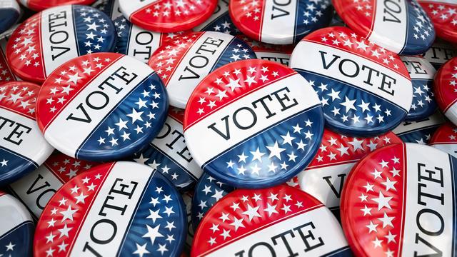 Großer Stapel von Wahlbuttons mit den Farben der amerikanischen Flagge. Darauf steht "Vote".