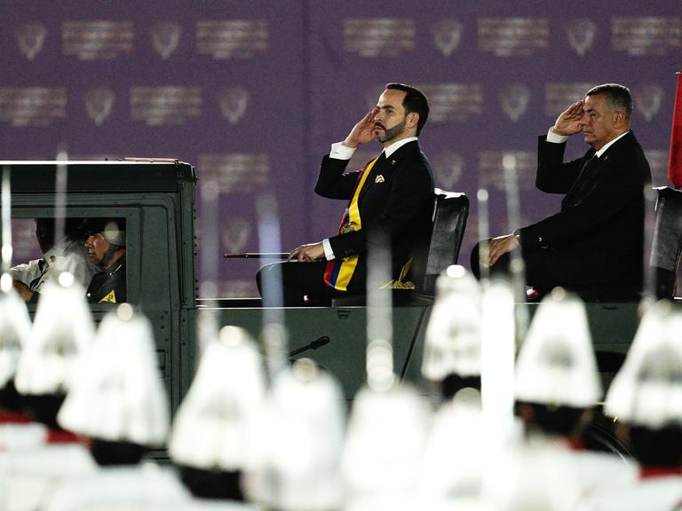 Der neue kolumbianische Präsident Abelardo de la Espriella nimmt nach seiner Amtseinführung in der Stadt Cali salutierend eine Militärparade ab. Im Vordergrund sind Helme zu sehen.  