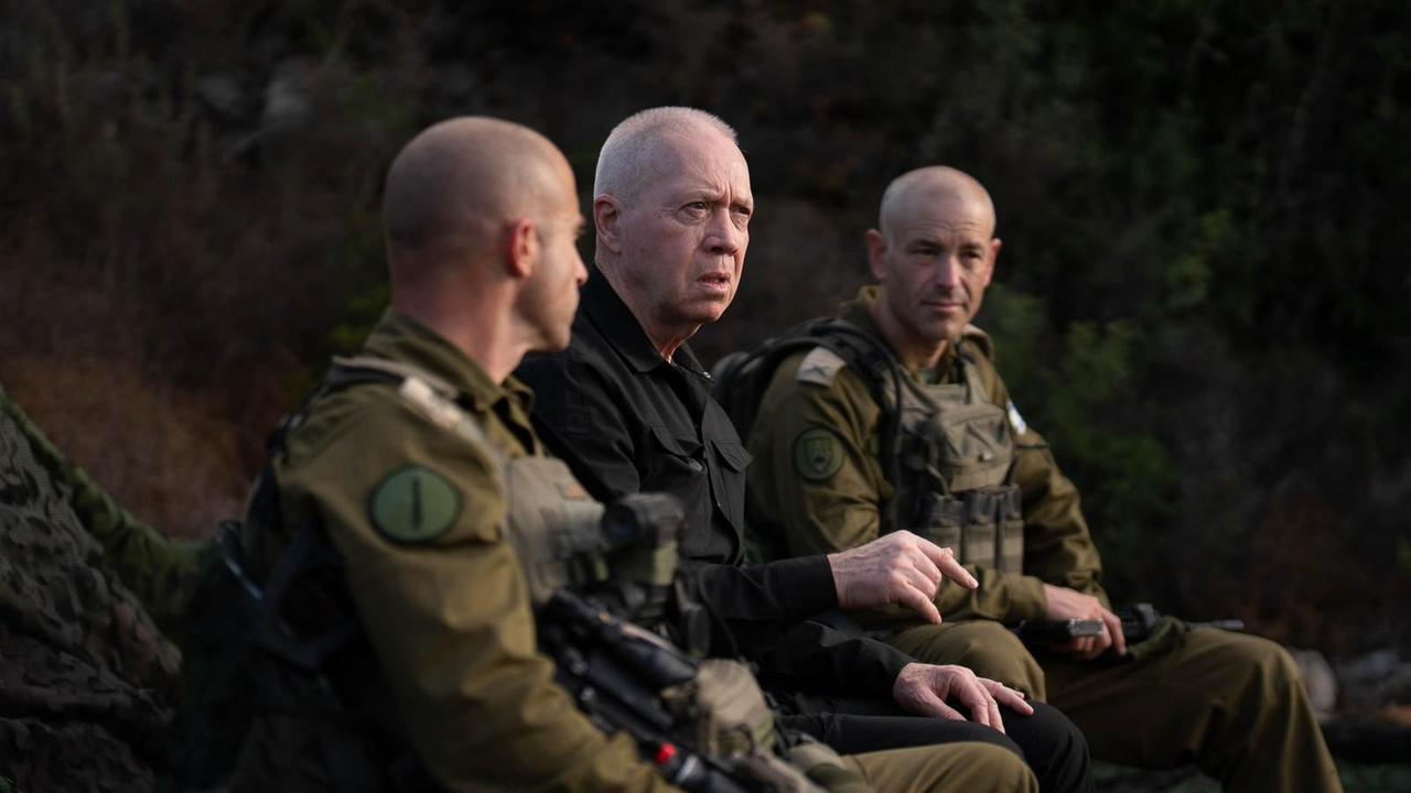 Verteidigungsminister Joaw Galant sitzt bei einem Besuch an der Nordgrenze Israels für ein Foto zwischen zwei Soldaten.