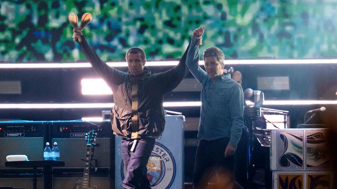 Liam Gallagher (l.), hält die Hand von Noel Gallagher von der Band Oasis während ihres Reunion-Konzerts am Freitag, 4. Juli 2025, in Cardiff
