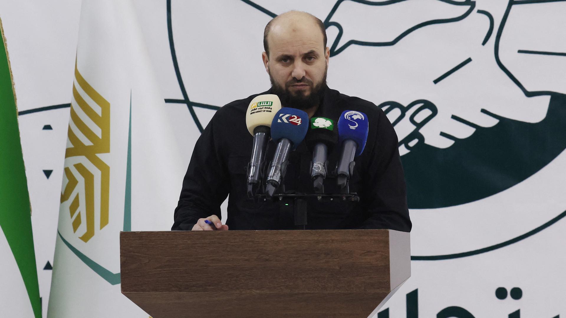 Mohammed al-Baschir steht hinter einem Rednerpult und spricht in Mikrofone. Mohammed al-Baschir steht hinter einem Rednerpult und spricht in Mikrofone.