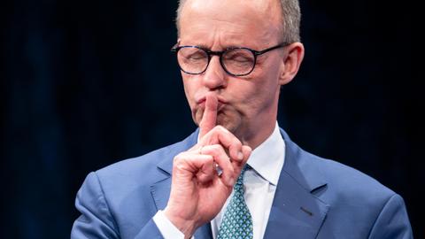 Friedrich Merz legt als "Ruhe-Zeichen" den Finger auf die Lippen