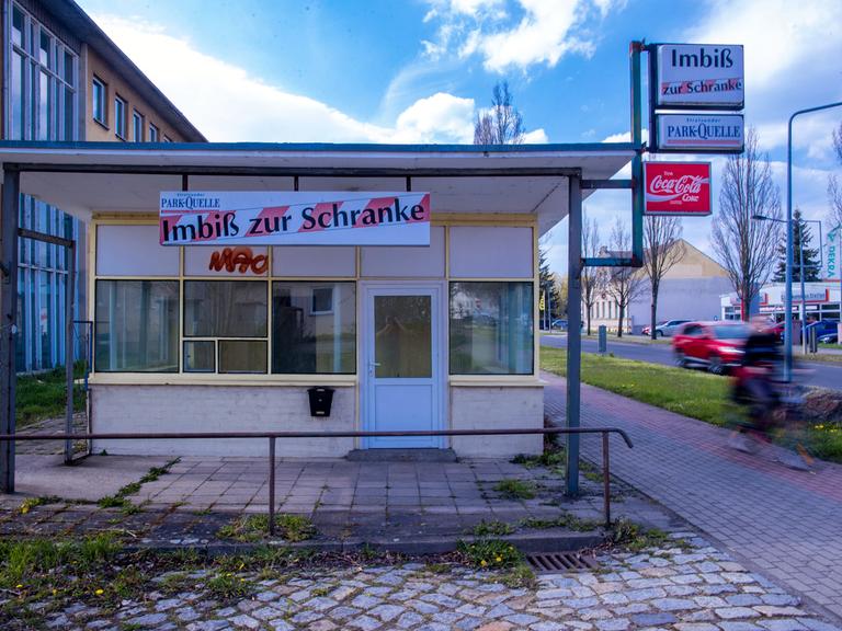 Ein Radfahrer fährt an einem leerstehenden Schnellimbiss vorbei.