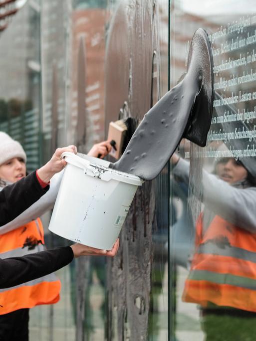 Die sogenannte Letzte Generation kippt Öl auf einer Skultptur der Grundgesetztafeln am deutschen Bundestag in Berlin.