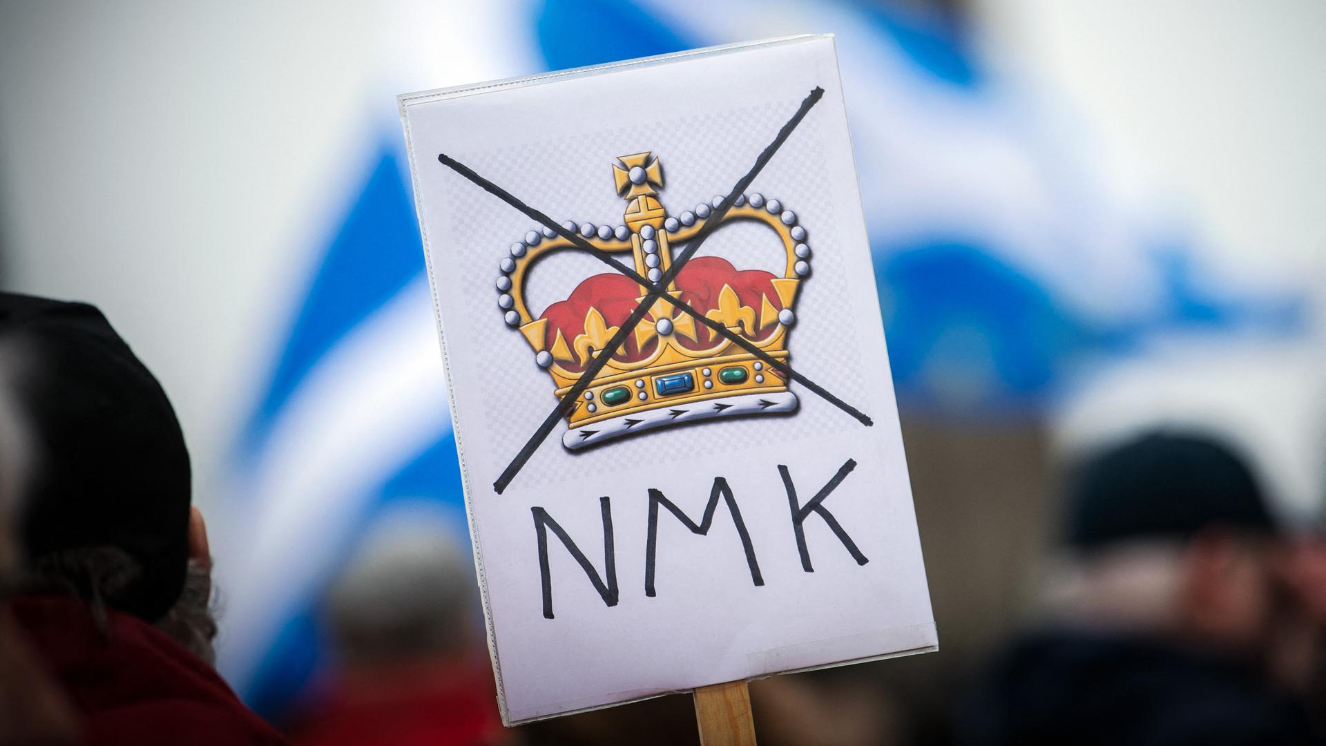 Auf einem Plakat ist die britische Krone durchgestrichen. Darunter stehen Großbuchstaben NMK.