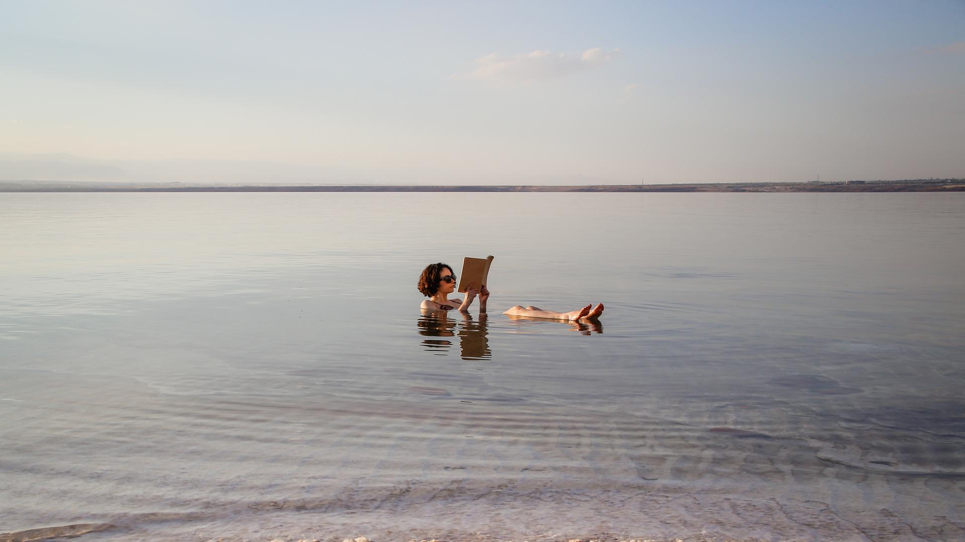 Eine Frau liest ein Buch im Toten Meer in Jordanien.