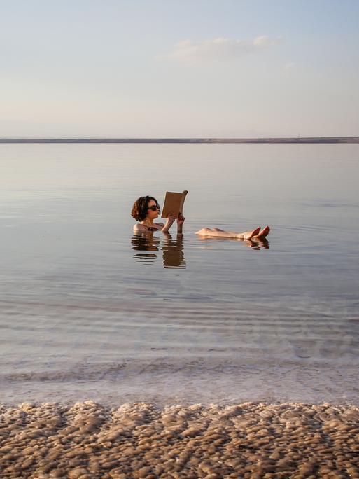 Eine Frau liest ein Buch im Toten Meer in Jordanien.
