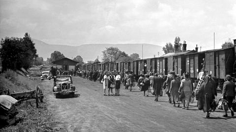 Auf einer schwarz-weiß-Aufnahme von 1946 sind Menschen zu sehen, auf Güterzüge zulaufen. Abgebildet sind Deutsche, die nach dem Ende des Zweiten Weltkriegs aus Tschechien ausgesiedelt wurden. 
