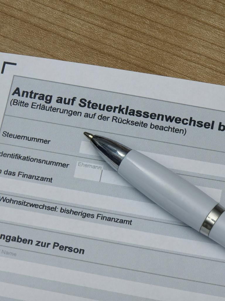 Auf einem ausgedruckten Antragsformular liegt ein Kugelschreiber. Das Formular trägt die Überschrift „Antrag auf Steuerklassenwechsel bei Ehegatten“ 