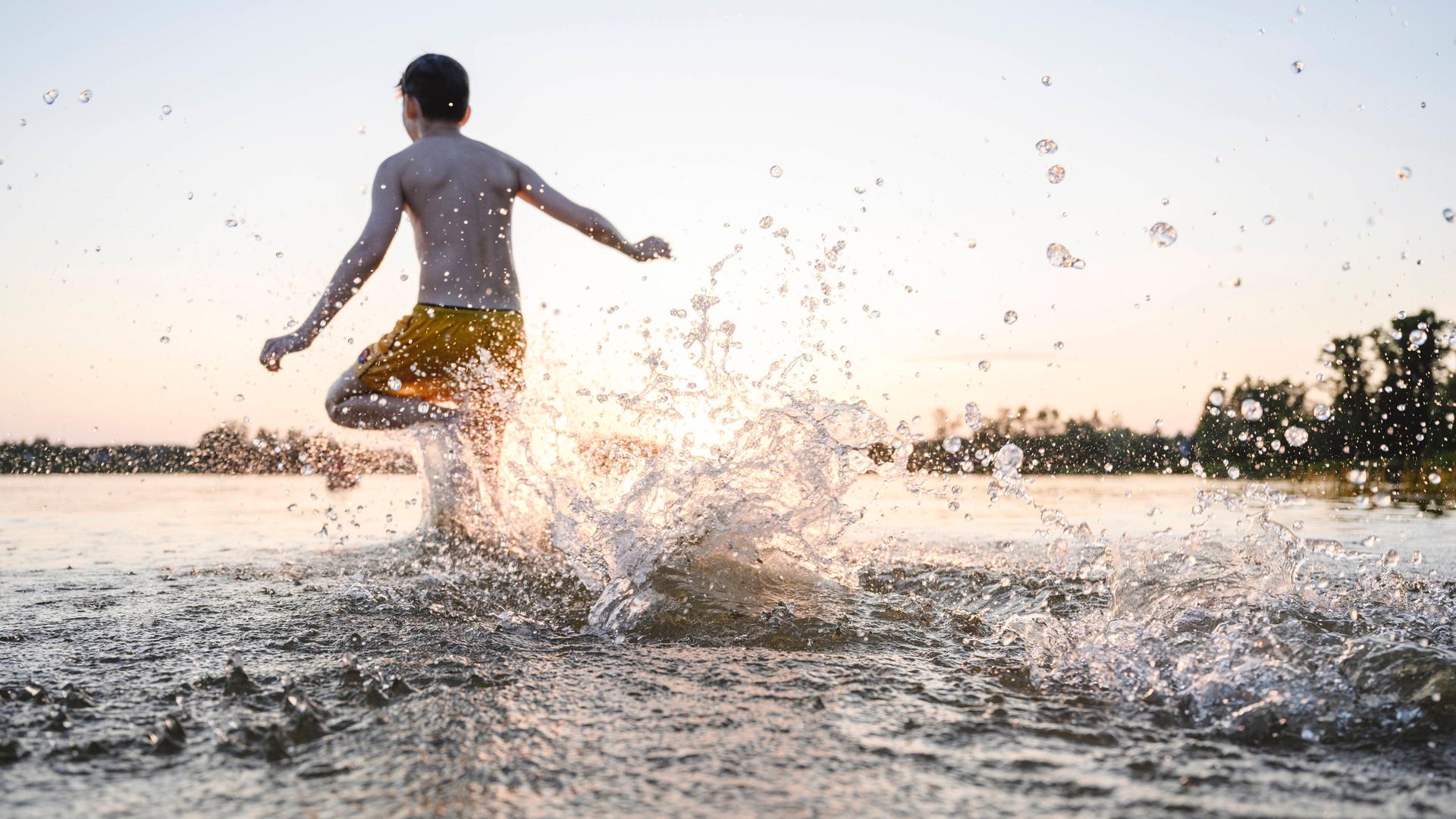 Ein Junge rennt zum Schwimmen ins Wasser. Ein Junge rennt zum Schwimmen ins Wasser.