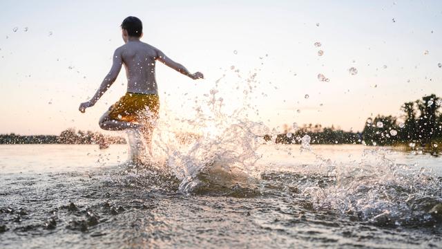 Ein Junge rennt zum Schwimmen ins Wasser.