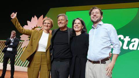 Felix Banaszak, Annalena Baerbock, Robert Habeck und Franziska Brantner jubeln gemeinsam auf einer Bühne bei der 50. Bundesdelegiertenkonferenz der Grünen in Wiesbaden.