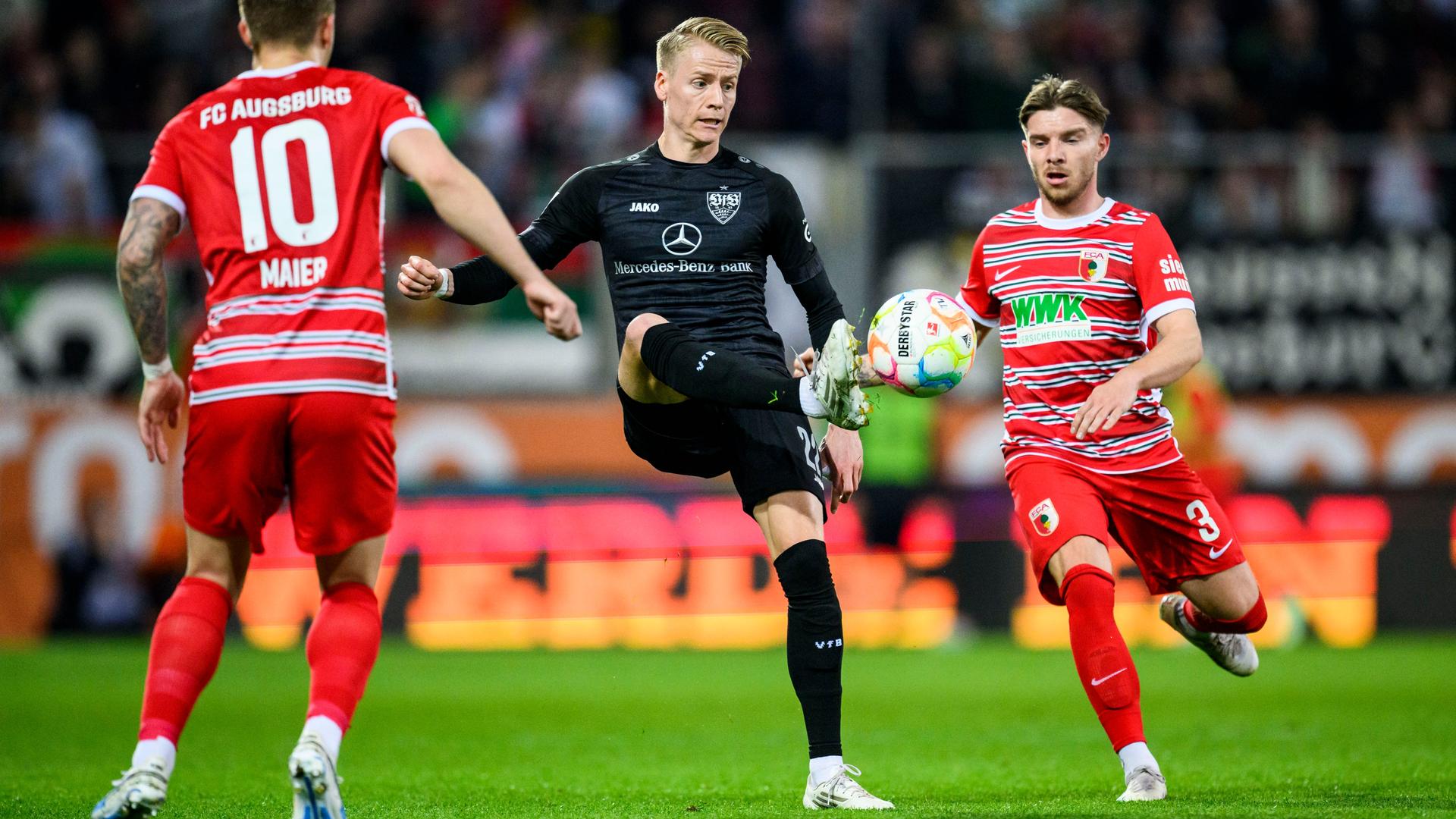 Fußball-Bundesliga: Das Foto zeigt Stuttgarts Chris Führich (M) in Aktion gegen Augsburgs Arne Maier (l) und Augsburgs Mads Pedersen (r)