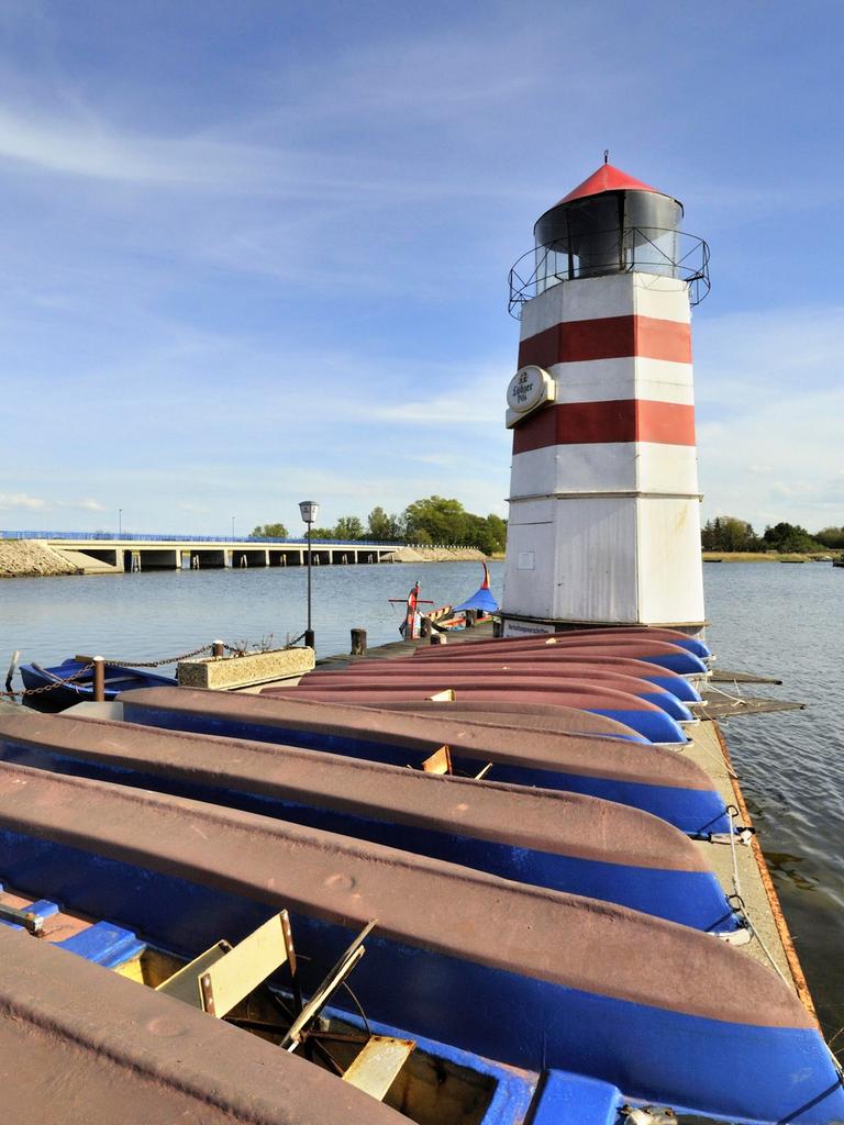 Blick auf den Bootshafen mit Leuchtturm auf der Insel Ummanz. Dahinter ist die Verbindungsbrücke nach Gingst auf der Insel Rügen zu sehen.
