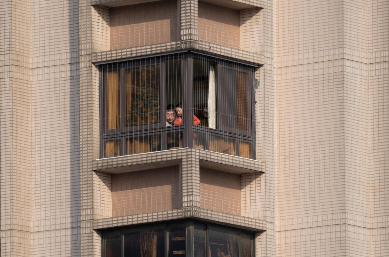 Ein Mann und ein Kind schauen am 2. Mai 2022 aus dem Fenster ihres Hauses während des Lockdowns in Shanghai.

