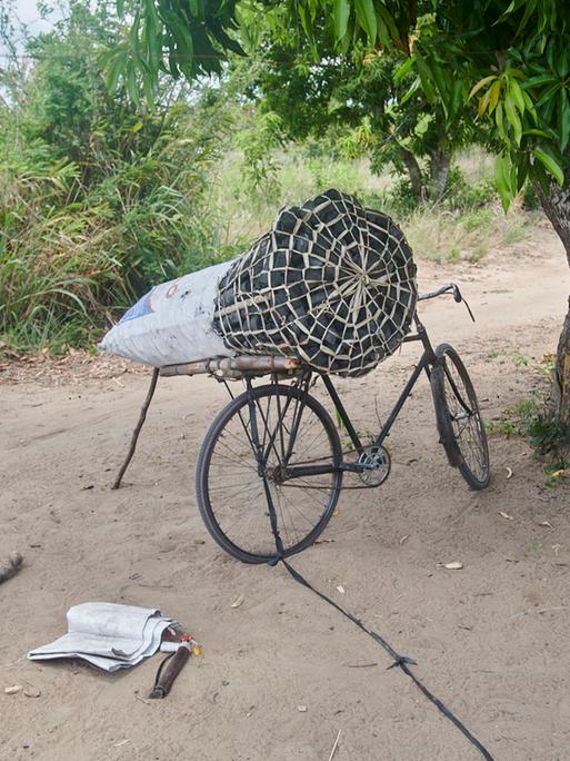 Ein Fahrrad, auf dem ein Sack Holzkohle befestigt ist