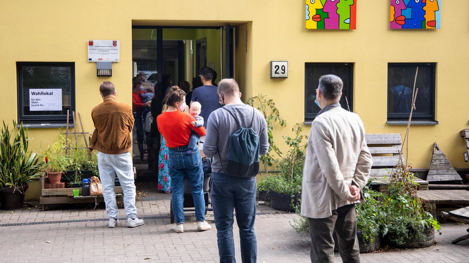 Menschen warten in der Stadt Berlin vor einem Wahl-Lokal.