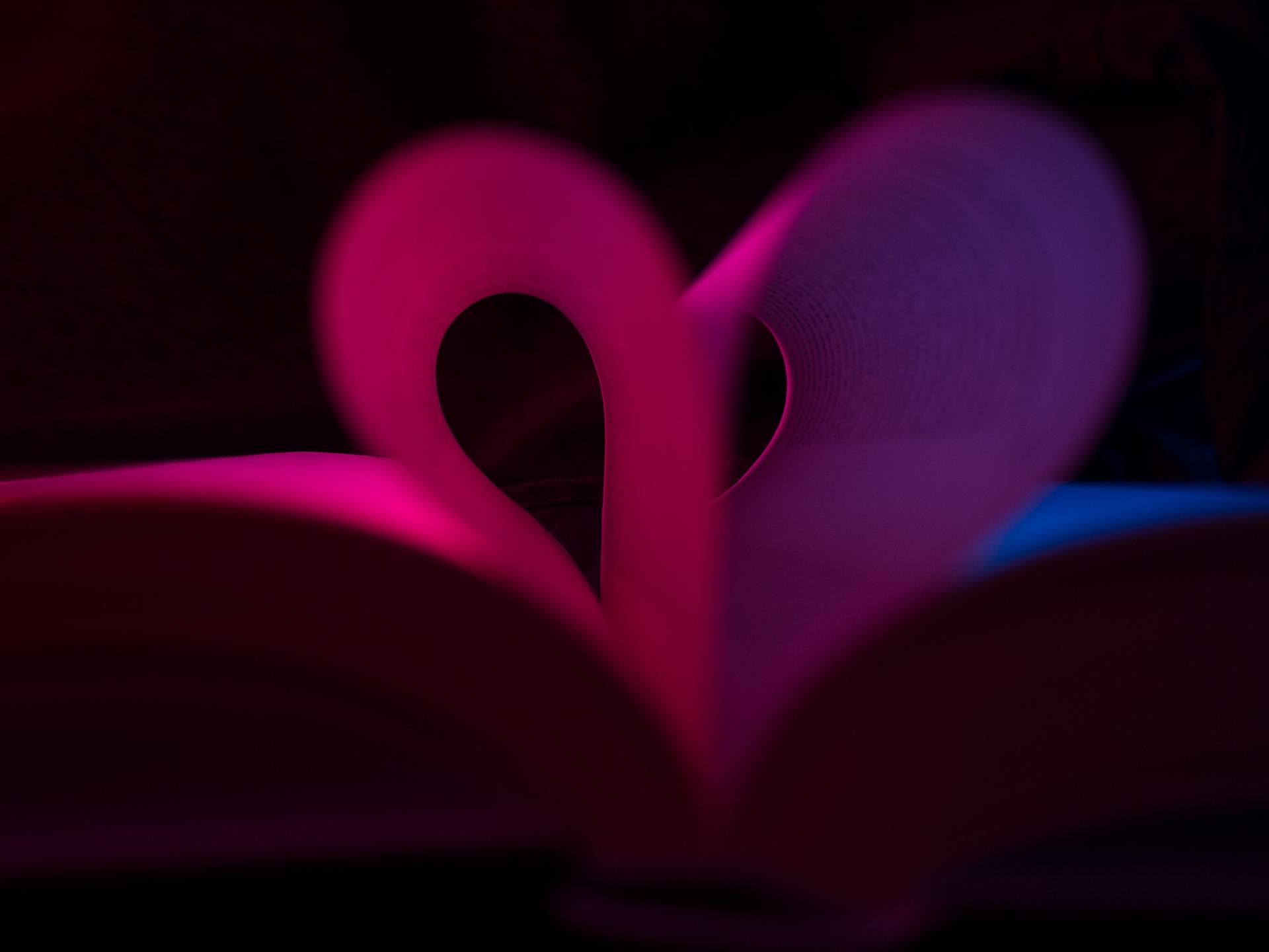 Illustration: Buch mit Seiten in Herzform. Dunkler Hintergrund