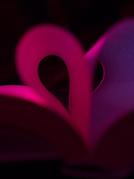 Illustration: Buch mit Seiten in Herzform. Dunkler Hintergrund